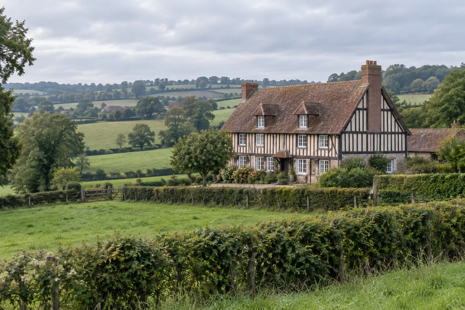 Maison à pans de bois au milieu des prairies bocagères du pays d’Auge.
